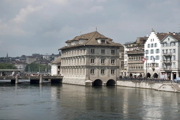 Im Hintergrund ist das Zürcher Rathaus zu sehen, welches unmittelbar im Fluss Limmat steht.